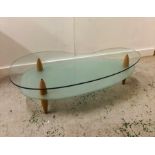 A Contemporary kidney shaped coffee table on three legs with a frosted glass lower shelf.