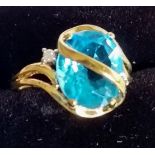 A 9ct yellow gold ring set with a blue topaz and a small diamond on either side, size M 1/2, 3.68g