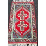 A Turkish hand-knotted oblong rug with multicoloured isometric decoration, double border with long