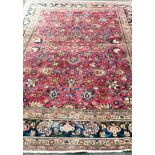 An Oriental burgundy-ground hand-woven multi-coloured wool drawing room rug with floral