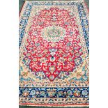 An Oriental scarlet-ground hand-woven multi-coloured wool drawing room rug with floral decoration,