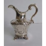 A Victorian silver cream jug with embossed foliate and rococo decoration on four cast feet, London