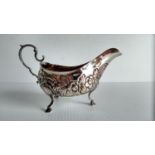 A George III Irish silver sauce boat of helmet form with embossed floral decoration, c-scroll handle