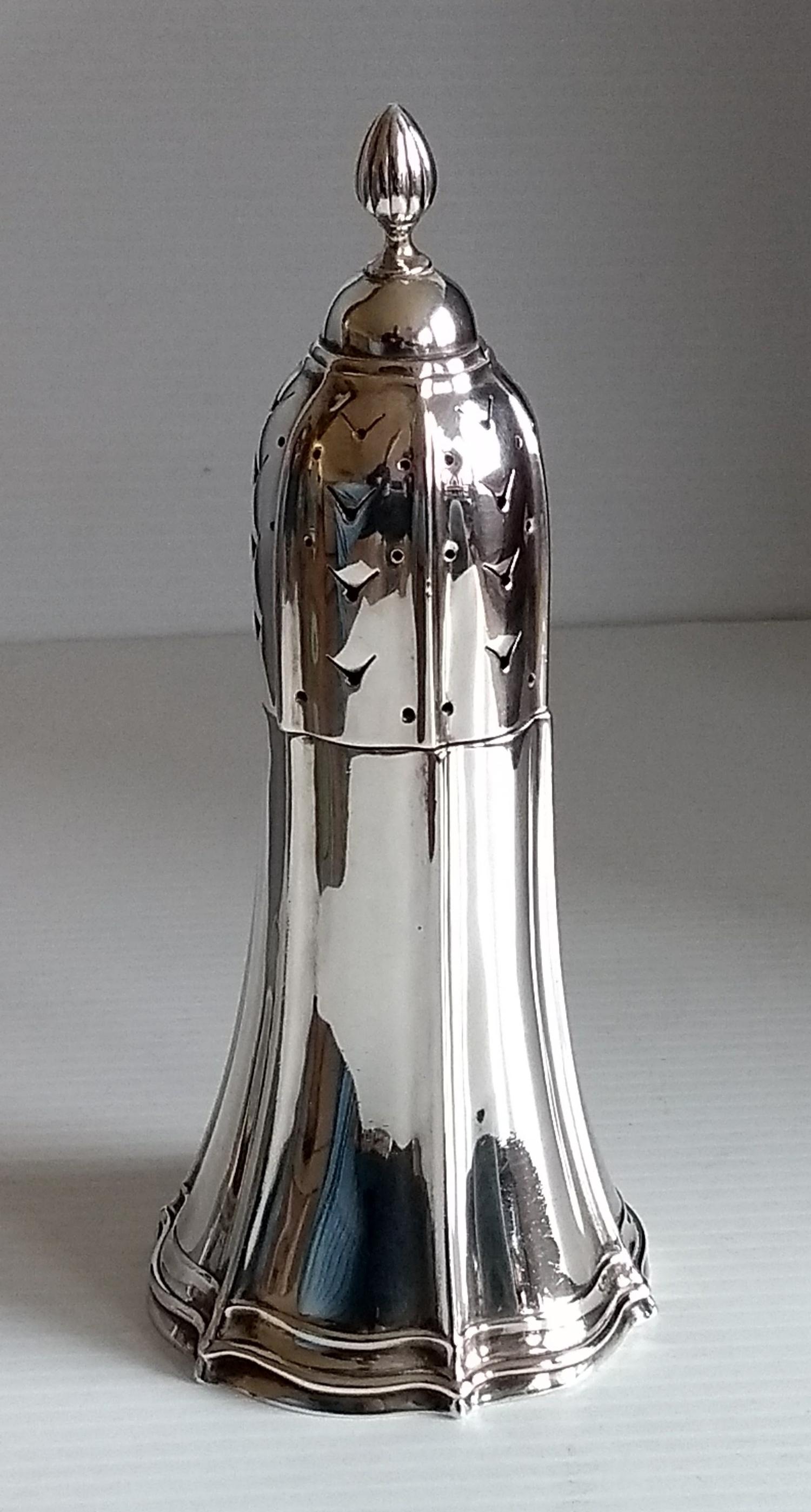 A George V silver sugar caster of conical form with fluted decoration, pierced fluted cover and