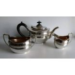 A George V silver three-piece tea service with ebony handle to teapot, fluted-rim decoration by CS