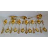 A set of twelve early 20th century silver 800, gilt tea spoons, sugar tongs and strainer with rococo