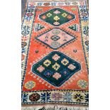 A Baluch hand-knotted orange-ground wool rug with multi coloured isometric design, medium fringe, in