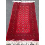 A burgundy-ground hand-knotted Baluch rug with single border and long fringe, in very good