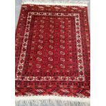 An Oriental burgundy-ground hand-knotted bokhara rug with double border and long fringe, 210 x 132