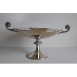 An Art Deco silver tazza with lion mask scroll handles, carved decoration to rim, knop and footrim