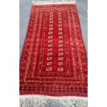 An Oriental burgundy-ground hand-knotted bokhara runner with triple border and long fringe, 240 x