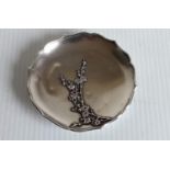 A Meiji period silver pin tray with wavy rim and applied prunus tree decoration on three stylized