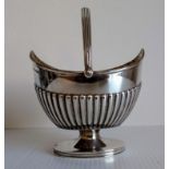 An Edwardian silver swing-handle sugar boat with fluted decoration on a single foot by Roberts &