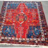 An Oriental blue-ground hand-knotted rug with multi-coloured isometric designs, double border and