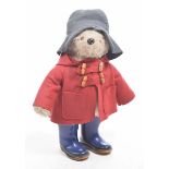 A light brown plush Paddington Bear With glass eyes, red duffel coat,