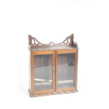 An Edwardian stained hardwood and glazed wall hanging bookcase With a moulded cornice above two