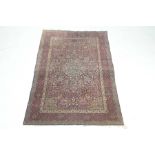A Kashan style rug The magenta and ivory coloured ground rug, with geometric border,