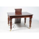A Victorian style mahogany extending dining table On lobed tapering legs and brass castors,