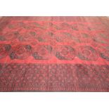 An Afghan style carpet The rich red ground with central panel filled with twenty-seven hexagonal
