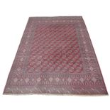 A red ground Bokhara style carpet The tasselled carpet with geometric borders,
