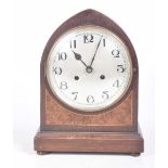 An early 20th Century walnut cased mantle clock With an arched case and an 18cm silvered dial
