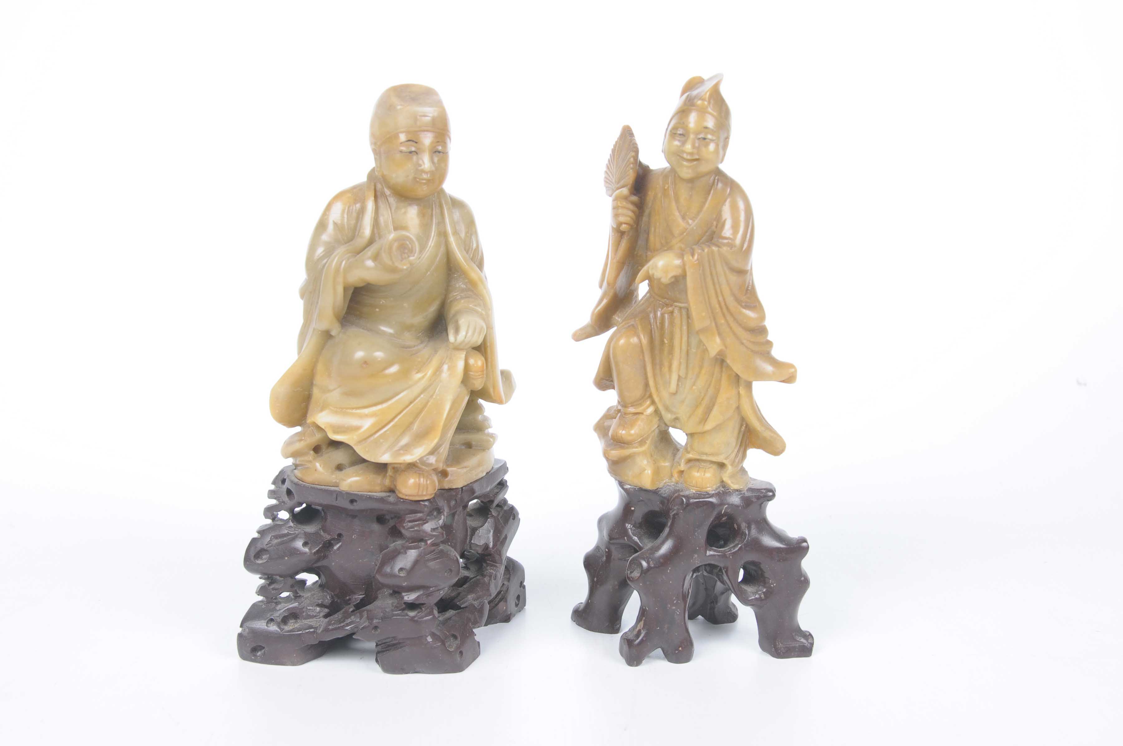 Two Chinese carved hardstone figures of immortal gods Each carved on a rocky outcrop,