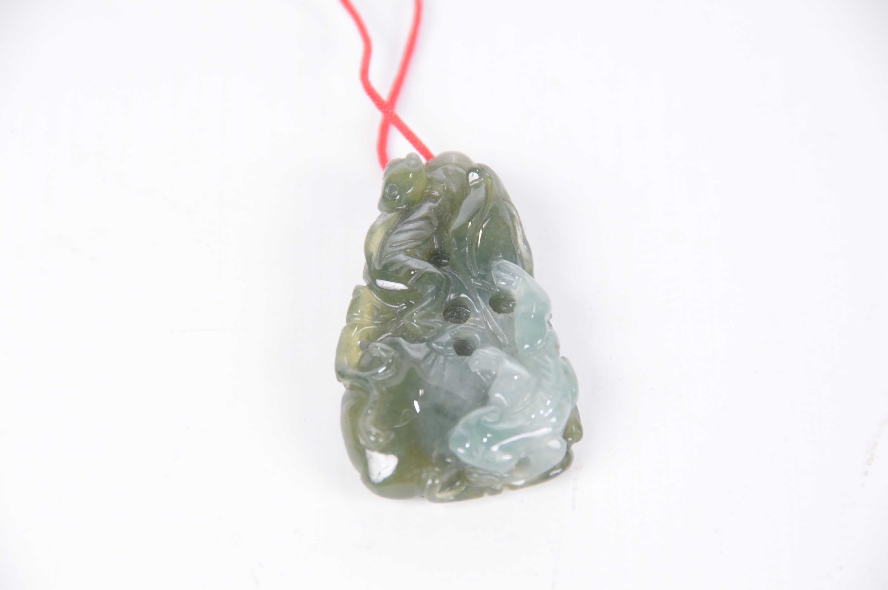 A Chinese green hardstone pebble pendant The variegated green hardstone pendant depicting two