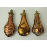 Three copper and brass powder flasks mid 19th Century First with elaborate floral decoration,