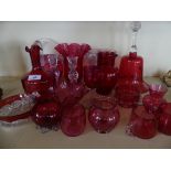 A collection of various cranberry and clear glassware to include a range of jugs, vases, large bell,