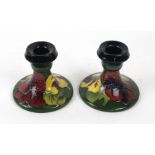 A pair of Walter Moorcroft candlesticks Decorated in the Hibiscus pattern on a green ground,