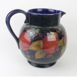 A large Walter Moorcroft pottery jug of bulbous form Decorated in the Pomegranate pattern on a blue