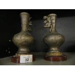 A pair of Continental base metal vases with cherub decoration, raised on red marble plinths