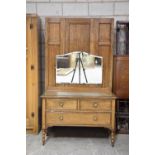A 1930's oak two piece bedroom suite The single wardrobe with a panelled door above a single