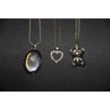 Three necklaces To include a diamond locket, a cubic zirconia heart pendant and one other, stamped