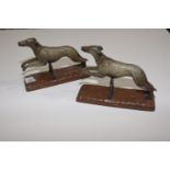 A pair of cold painted pewter greyhound bookends The greyhounds modeled leaping over hedge. Height