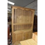 A pine bookcase dresser With a moulded cornice above three adjustable shelves and a pair of cupboard