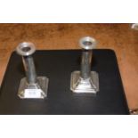 A pair of early 20th Century candlesticks Each with a square base, with cylindrical stem and
