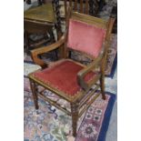 An Edwardian walnut low seat elbow chair Having a padded back above down swept and channeled arms