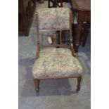 An Edwardian rosewood and upholstered nursing chair Having a padded back above a pierced and