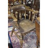 A Edwardian elm and beechwood smokers elbow chair by Gibbon's The curved top rail raised on turned