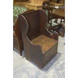 A 19th Century oak lambing chair The board back flanked by shaped wing backs above a hinged box