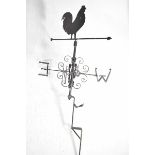 An iron weather vane Having a cockerel silhouette above a revolving pointer with scrolling