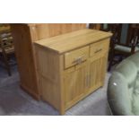 A contemporary light oak sideboard Having a rectangular slab top above two frieze drawers and two