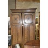 A 1920's oak wardrobe Having a carved and moulded cornice above two panelled doors each centred with