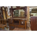 A late Victorian walnut mirror back sideboard Having a leaf carved broken pediment above a flower