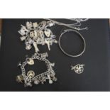 A selection of silver and white metal jewellery To include two charm bracelets, a bangle, pendant