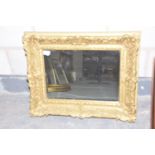 A contemporary gilt framed wall mirror The rectangular wall mirror with ornate gilt scrolling frame,