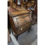 A 1920's oak bureau Having a geometrically moulded fall front above two conforming moulded drawers