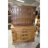 A 19th Century pitch pine kitchen dresser Having a moulded cornice above a scalloped frieze and