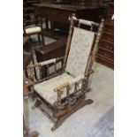 An early 20th Century stained beechwood Amercian rocking chair The padded back and seat supported on